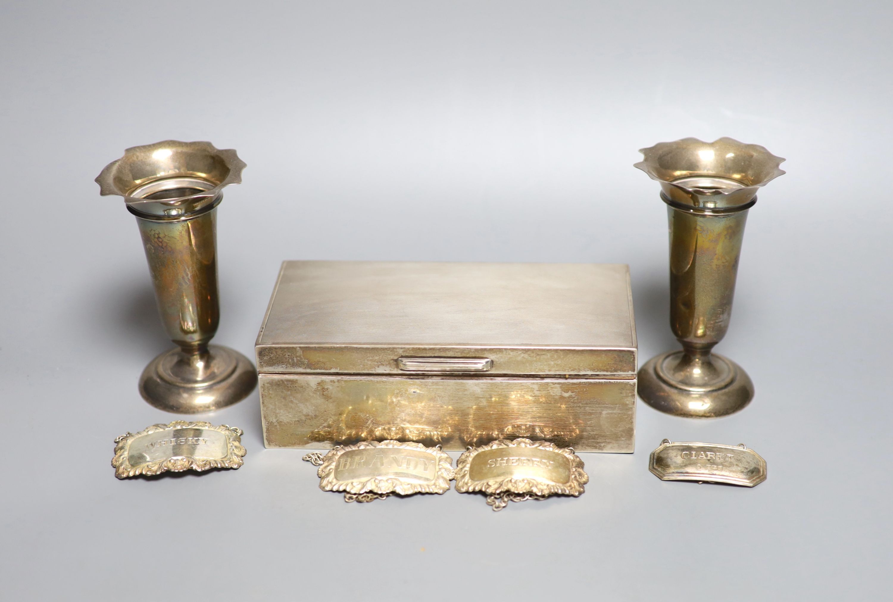 A pair of Edwardian silver vases, Birmingham, 1908, 11.1cm, weighted, four modern silver wine labels and a silver mounted cigarette box.
